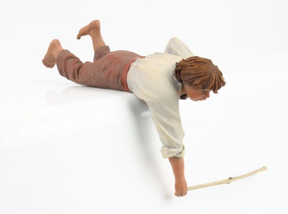 Niño tumbado con palo 15 cm.